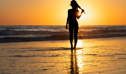 Woman walking along the beach at sunset with flowing hair © Raquel