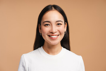 Smiling asian woman wearing white t-shirt isolated on beige background