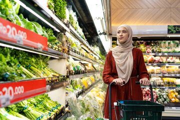 Happy mature Asian woman looking  products at grocery store. Costumer buying food at the market. Woman enjoying her time shopping at the grocery store