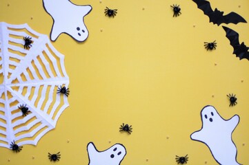 Halloween composition with spiders, pumpkins, cobwebs, bats and ghosts on an yellow background...