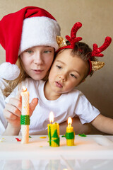 Portrait of children with candles in New Year hats on eve of Happy New Year at home Merry Christmas