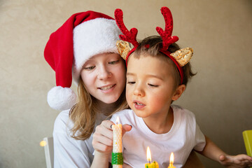 Boy and girl teenager with candles in New Year's hats at home and Merry Christmas.