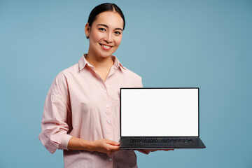 Beautiful Asian woman smiling holding laptop with blank screen for advertisement, mockup, copy space