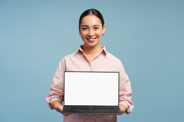 Smiling businesswoman showing laptop with blank screen on blue background