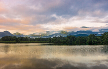 The warm dawn lighting the pond, the forest, and the mountain range