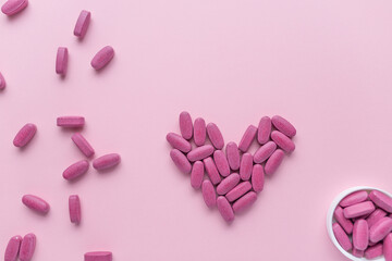 Pink tablets pills on pink background. Woman's health concept. Vitamins and supplements for women 