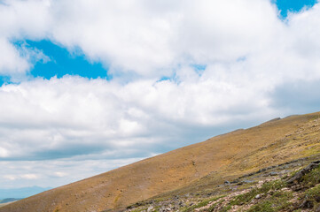 The barren slopes under the blue sky and white clouds