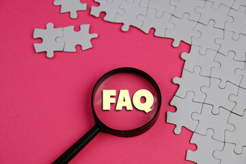 text of FAQ acronym of frequently asked question under magnifying glass on management and business...