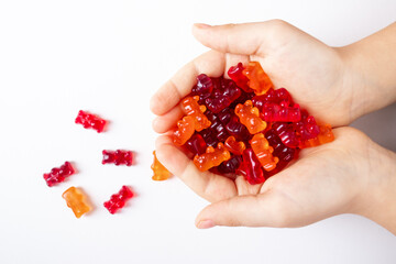 child holding in hands colourful  gummy bears, natural backdrop, creating a vibrant scene