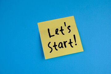 text Lets start on a yellow note pad and pen on isolated blue background