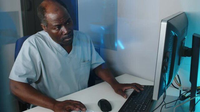 Mature African American radiographer working on desktop computer in his office, high angle view shot, copy space