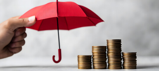 Financial Protection Concept with Stacked Coins under Red Umbrella