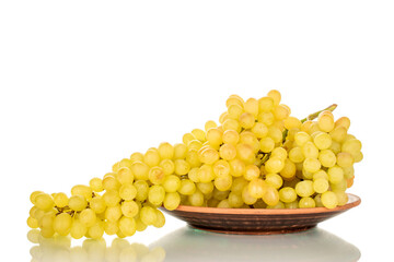 One bunch of ripe white grapes in a clay plate, macro, isolated on white background.