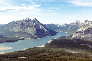 high angle view of a valley with a turquoise lake and mountain peaks in the distance in summer on a sunny day