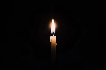 Fototapeta premium Solitary candle flame illuminates darkness in a meditative scene