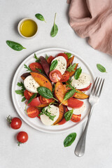 Peaches, tomatoes, mozzarella salad in plate on  white background. Caprese italian traditional salad top view