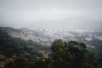 A panoramic view of the village in Monsanto, Portugal, as fog rolls down into the valley, covering the landscape in a serene and mystical blanket.