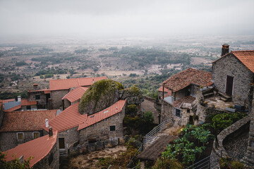Obraz premium Portuguese houses in the village of Monsanto, Portugal, slowly disappearing into the fog as it descends into the valley, creating a peaceful and mystical scene.