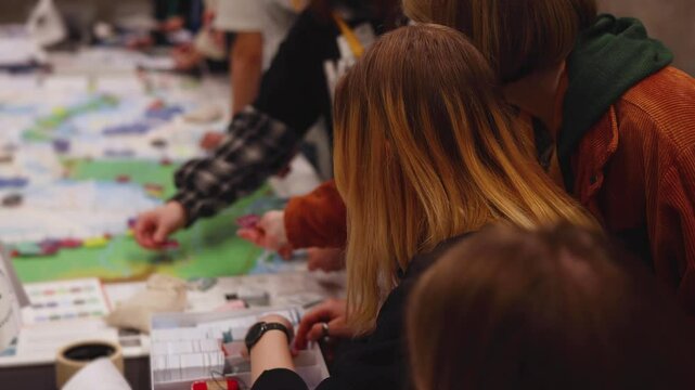 Process of playing tabletop board game on the table, fun with friends and family in room indoors, board game concept, company group of students adults play board games, roll the dice on a game map