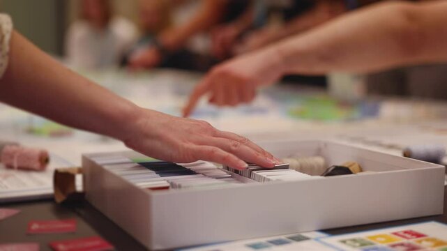 Process of playing tabletop board game on the table, fun with friends and family in room indoors, board game concept, company group of students adults play board games, roll the dice on a game map