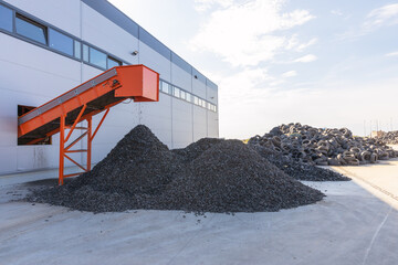 Tire recycling facility with shredded rubber piles and conveyor belt