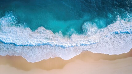 Aerial view of crystal-clear blue water and a golden sandy beach with sunlight enhancing the waves and shoreline
