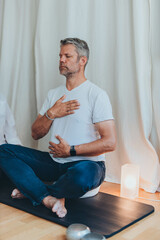 A man sitting in lotus position, the man wearing a blindfold while practicing breathing exercises...