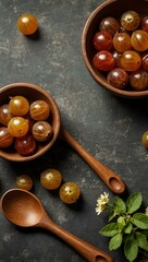 Gooseberries with wooden spoons and oregano flowers on a kitchen table.