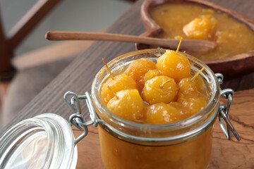 Glass jar of apple jam on wooden olive board. Home made fruit from garden. Kitchen interior and organic food. 