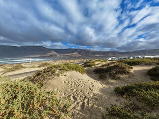 Sand dunes and mountain on Famara beach with blue sky and clouds in Lanzarote, Spain