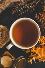 Autumn flat lay with a cup of tea, jar candle, cupcake, dried flowers, and cozy knit fabric creating a warm and inviting atmosphere