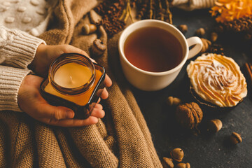 Girl holding a burning candle in her hands, cozy autumn