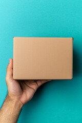 Fototapeta premium A person holding a plain brown box against a vibrant blue background in a bright setting