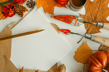 Autumn still life with brushes, paints, maple leaves and blank postcard on white background. Perfect for creative projects, autumn greetings and art ideas