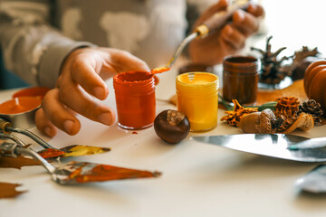 Creative autumn art activity with paint and natural materials like pine cones, acorns, and chestnuts, crafting seasonal decorations