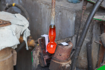 Worker of crystal glass manufacture is making drinkware.