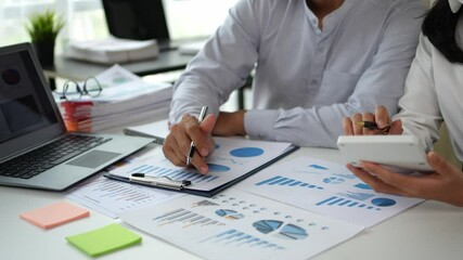 Business team members collaborate, analyzing financial data and using a calculator in a professional office setting