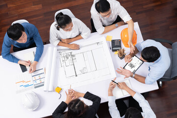 Top view banner of diverse group of civil engineer and client working together on architectural project, reviewing construction plan and building blueprint at meeting table. Prudent