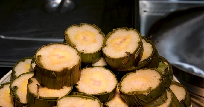 Cooked glutinous rice cake, Vietnamese new year food tet buffet Vietnam New Year rice cake in palm leaf with peas and meat slice on grey plate