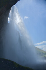 The waterfall of Seljalandsfoss in Iceland from behind the water