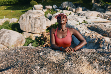 Woman in a sports outfit relaxing on a rock formation in nature