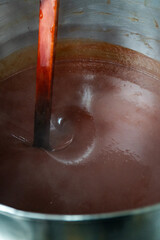 Stirring Rosehip Jam in Artisan Factory.  The large stainless-steel pot holds the simmering jam, with a spatula gently stirring the thick mixture. 