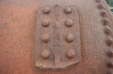 rough iron plating on an old iron compressor. Old rusty compressor. Corrosion texture and color. Rivets, plating, iron. Industrial, industrial boiler.