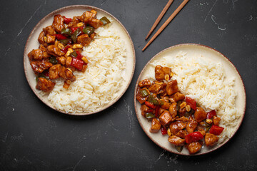 Two plates with Chinese kung pao chicken with rice, veggies, and peanuts in spicy sauce. Top view...