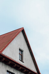 orange roof of a modern house with windows on the background of a gray cloudy sky