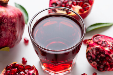 Glass of fresh pomegranate juice with pomeganate fruits on white marble background. Healthy refreshing drink