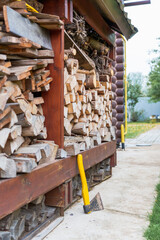 firewood in the yard, a stack of neatly chopped firewood is arranged by the side of a wooden cabin, with an axe resting against the pile