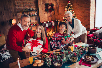 Photo of peaceful family sit table giving giftbox celebrate festive christmas time apartment indoors