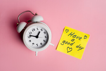 Retro white alarm clock and positive message on pink background for a cheerful start