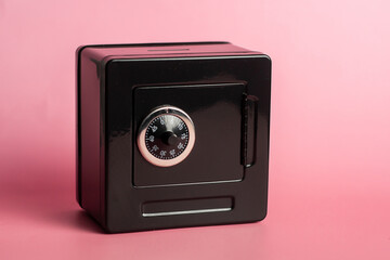 Black safe with combination lock on pink background